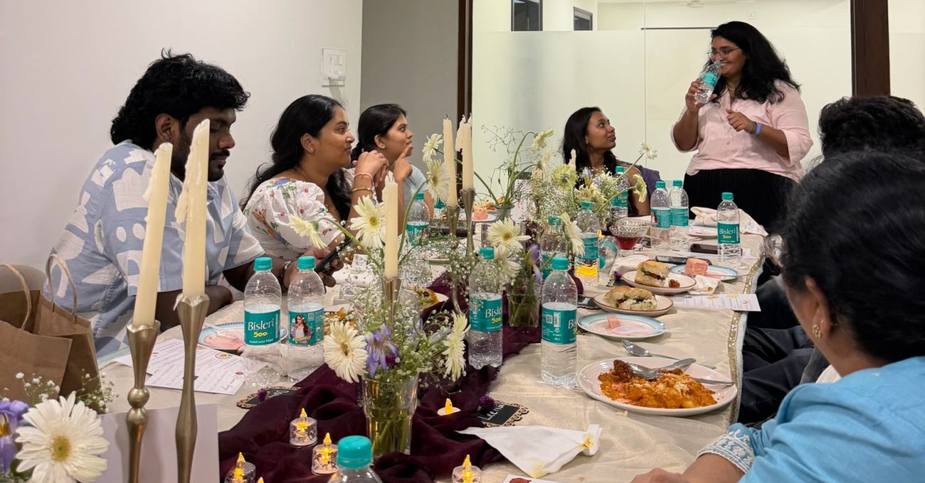 Ten guests mid-conversation at a P&A Table supper club dinner in Vijayawada