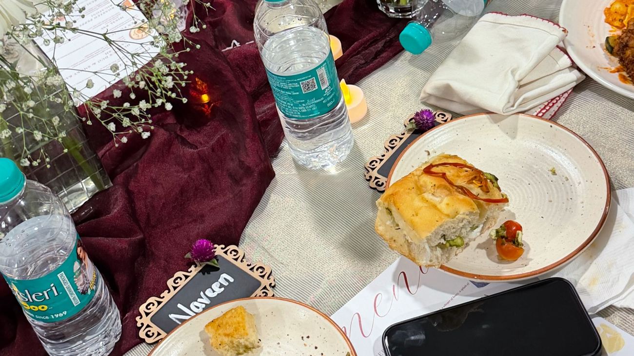 Table No. 01 mid-dinner — focaccia, name cards, and flowers down the runner at P&A Table, Vijayawada